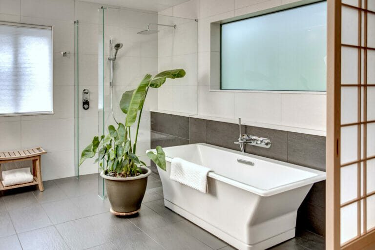 Unique plumbing fixtures at the beautiful square tulip-style bathtub and luxury rain shower and wand in the curbless, glass enclosed shower space. Tub is a DXV Modulous with a Hansgrohe Hose. Project Completed in 2020.