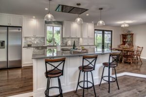 how long does a kitchen remodel take? Bellevue kitchen featuring island with 3 chairs, open design, bright open windows, statement lighting, and a modern fridge